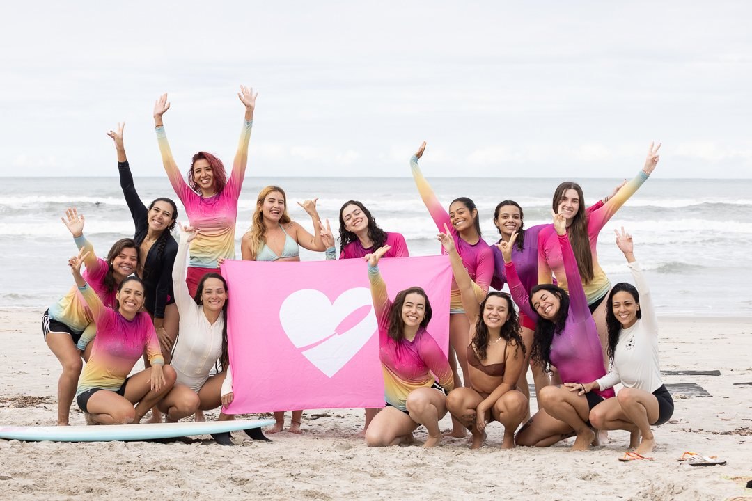 Grupo de mulheres reunido na praia durante uma experiência We Surf Girls