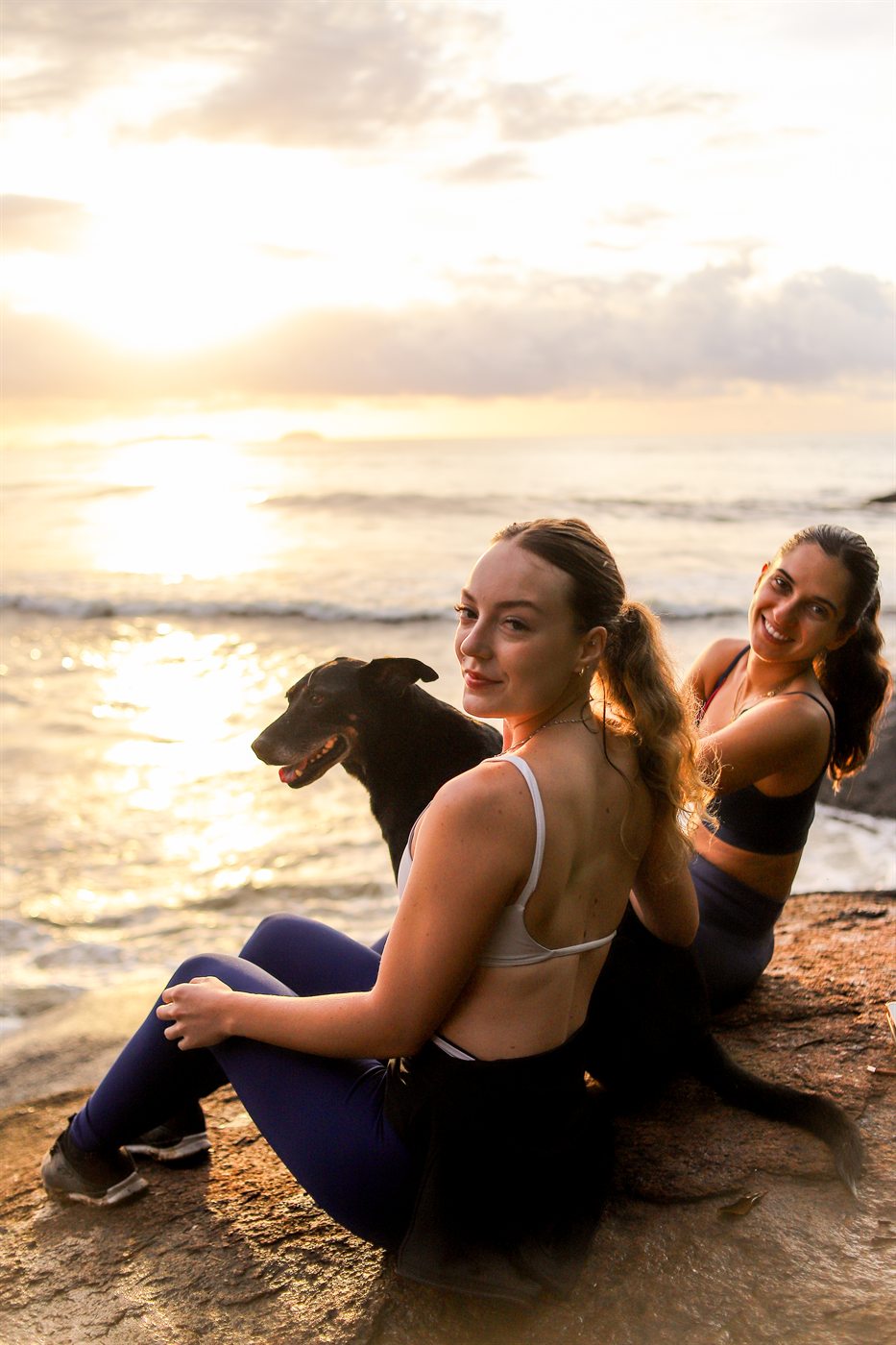 Amigas e um cachorro assistindo ao nascer do sol na praia